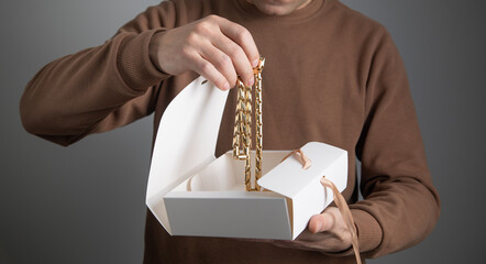 Man showing gift box with a golden necklace.