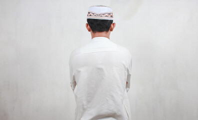 Portrait of a Muslim Asian man praying on a white wall background
