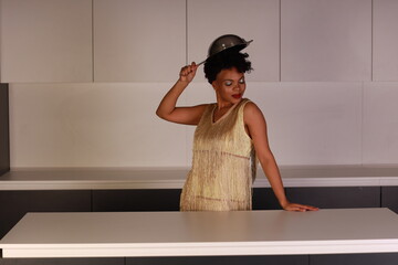 Beautiful woman with a colander on her head in the kitchen