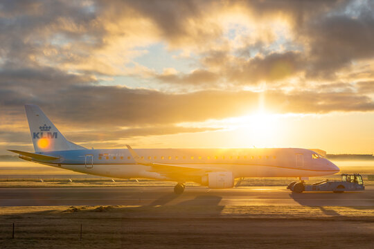 Sunrise silhouette of KLM Cityhopper Embraer jet towed with pushback truck in from of Amsterdam Skyline