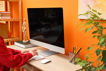 Woman working on computer at desk indoors, closeup