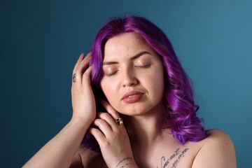 Obraz premium Beautiful woman with bright purple hair and tattoo in Latin on light blue background