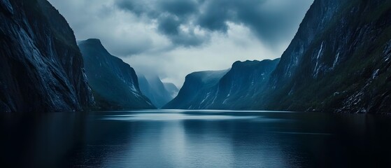 Breathtaking fjord landscape surrounded by rugged snow capped mountains with their dramatic reflections in the still dark blue waters below  The scene is enhanced by contemporary