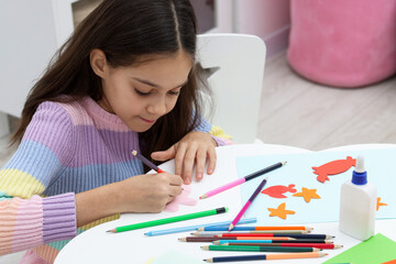 Girl drawing card at table indoors. Art and craft