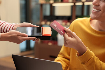 Man paying with credit card via terminal in cafe, closeup