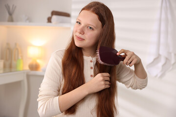 Beautiful teenage girl brushing her hair at home