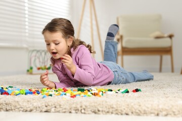Cute girl playing with building blocks on floor at home
