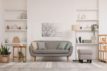 Stylish furniture, houseplants and different decor in light living room. Interior design