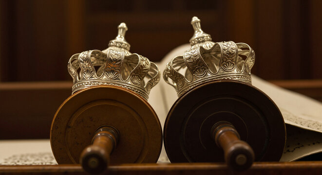 Torah scrolls with silver crowns, in a traditional style, representing Judaism and religious text