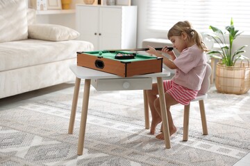 Cute little girl playing billiards at home