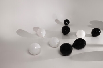 A composition of black and white balloons scattered on a smooth, neutral surface with soft shadows. Concept minimalism, contrast, and abstract celebration.