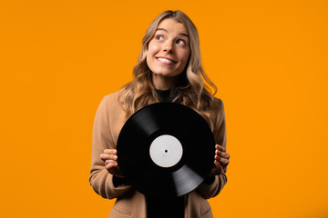 Pretty businesswoman dancing with vinyl record disc on yellow. Hobby,music lover