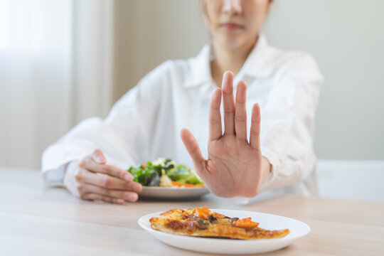 Diet concept, asian young woman close up hand push out away Pizza, refuse junk process, carb food on plate, choose green vegetable salad, eat low fat for good health. Female people getting weight loss