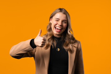 Positive businesswoman with hand sign like, thumbs up gesture. Lady on yellow background