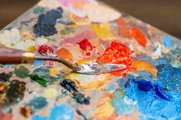 Obraz premium Old used palette knife, palette with multi-colored spots of oil or acrylic paint in an artist's studio