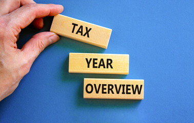 Tax year overview symbol. Concept words Tax year overview on beautiful wooden blocks. Beautiful blue background. Businessman hand. Business tax year overview concept. Copy space.