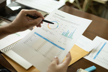 the businessman is sitting at a desk with a calculator and a stack of papers. She is looking at the...