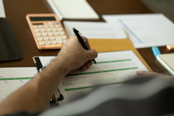 the businessman is sitting at a desk with a calculator and a stack of papers. She is looking at the...