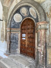 Old wooden door in an arched entrance of a historical building  showing discoloration and wear    