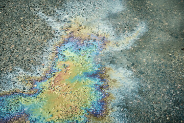 Oil Slick on Pavement Creates a Vibrant Pattern, Reflecting Colors Under Sunlight During Midday