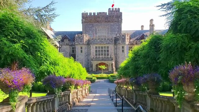 Hatley Castle through greenery and flowers, Victoria, BC, Canada. Hand held walking motion.