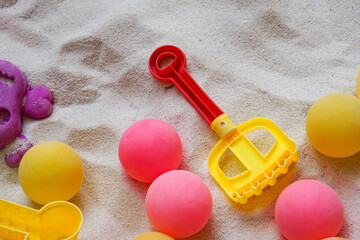 Colorful ball toys in children's sandbox with sand scooping equipment