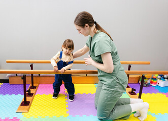 Young girl with cerebral palsy participates in rehabilitation exercises with a therapist at a...