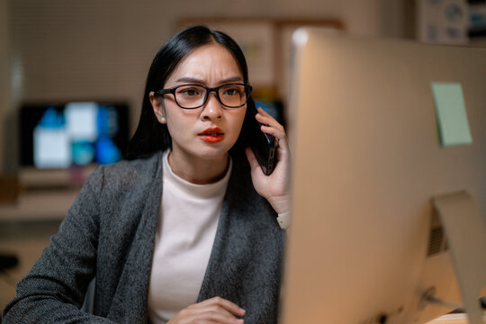 Stressed businesswoman working late at night in office having a difficult phone call