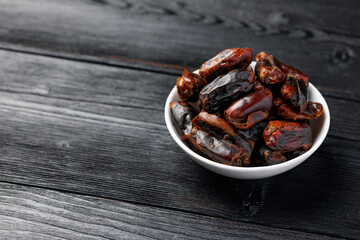 Dried sweet pitted dates in white bowl. Healthy food