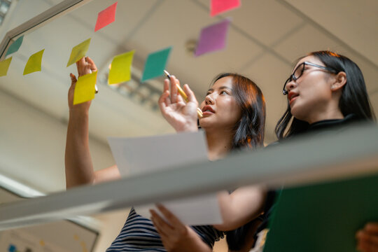 Businesswomen using sticky notes during a brainstorming session