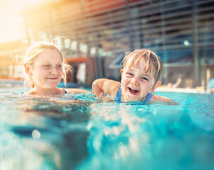 A mother and daughter joyfully play together in the swimming pool, embracing the fun and warmth of a perfect summer holiday.