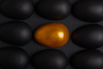 A creative designer postcard made of rows of halves of black eggs and a golden egg in the center.