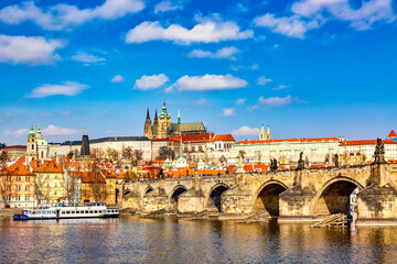 View of Charles Bridge, Prague Castle, sightseeing ship and Vltava river in Prague, Czech Republic. Nice sunny summer day with blue sky and clouds. Famous landmarks in Europe.