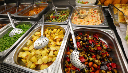 assortment of cooked vegetables in stainless steel trays at the self service restaurant
