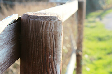Close-up of a wooden fence pole with green meadow in the background
