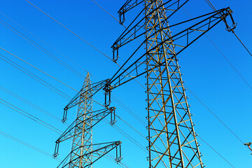 Bottom-up view on an electrical transmission post with blue sky in the background