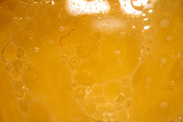 Abstract close-up of oil bubbles in yellow liquid on soft background