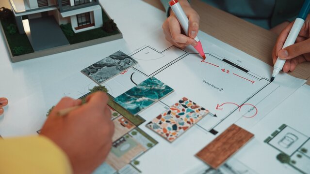 A team collaborates on an interior design project, sketching a floor plan while using color swatches and samples to enhance their creative process and ideas. SACTR
