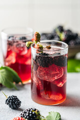 Delicious refreshing blackberry lemonade with fresh berries and ice on table against light background