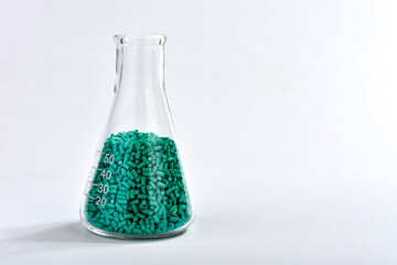 Turquoise masterbatch granules in Erlenmeyer flask isolated on white background, color pigment...