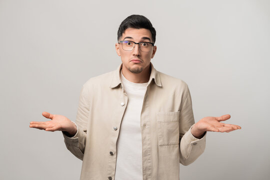 No clue. A man in a beige overshirt and eyeglasses raising his palms and shrugging his shoulders in confusion. A perfect mix of uncertainty and casual charm