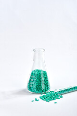 Turquoise masterbatch granules in Erlenmeyer flask and glass tube isolated on white background,...