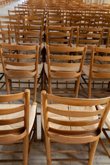 A serene interior view of a church featuring rows of simple wooden chairs, arranged in a quiet, contemplative setting