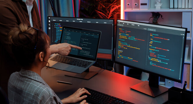 Serious of IT developers discussing intelligent website development coder system running data online two screens with laptop showing information network at neon light room at modern office. Infobahn.