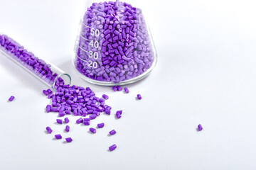 Purple masterbatch granules in Erlenmeyer flask and glass tube, isolated on white background, color...
