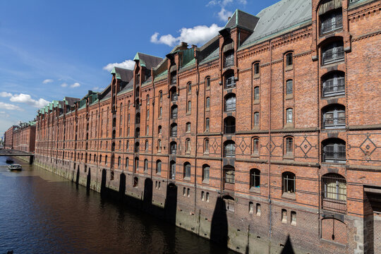 A view of the Hamburg Warehouse District (Speicherstadt), a UNESCO World Heritage site, with its red brick buildings, canals, and historic warehouses. - Powered by Adobe