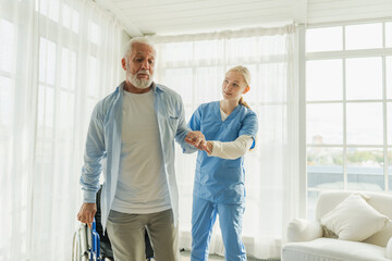 Rehabilitation healthcare. Physiotherapist nurse helps old man patient in wheelchair stand up...