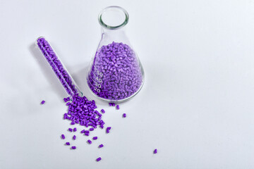Purple masterbatch granules in Erlenmeyer flask and glass tube, isolated on white background, color...