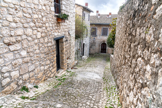 glimpse of a cobbled alley between stone houses in a charming medieval village in central Italy under a slightly cloudy sky