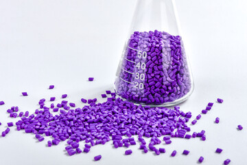 Purple masterbatch granules in Erlenmeyer flask isolated on white background, color pigment carrier...